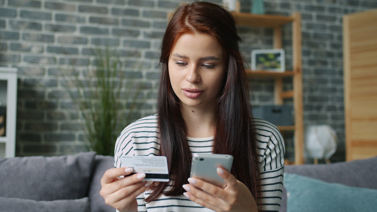 Woman completing an online purchase on a smartphone using a credit card, showing mobile checkout behavior in Latin America