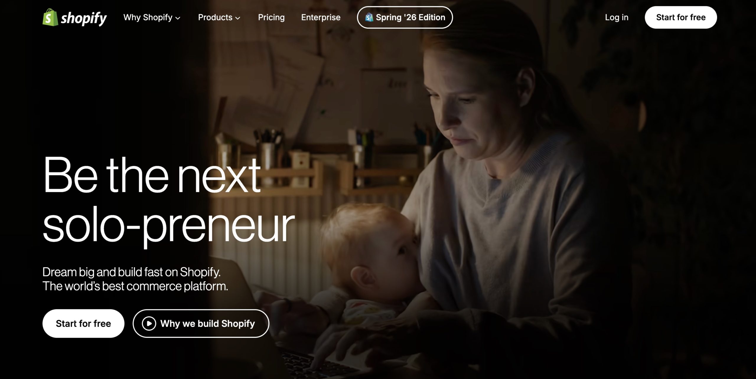 Shopify homepage hero reading Be the next solo-preneur, with a parent working on a laptop at night while holding a baby