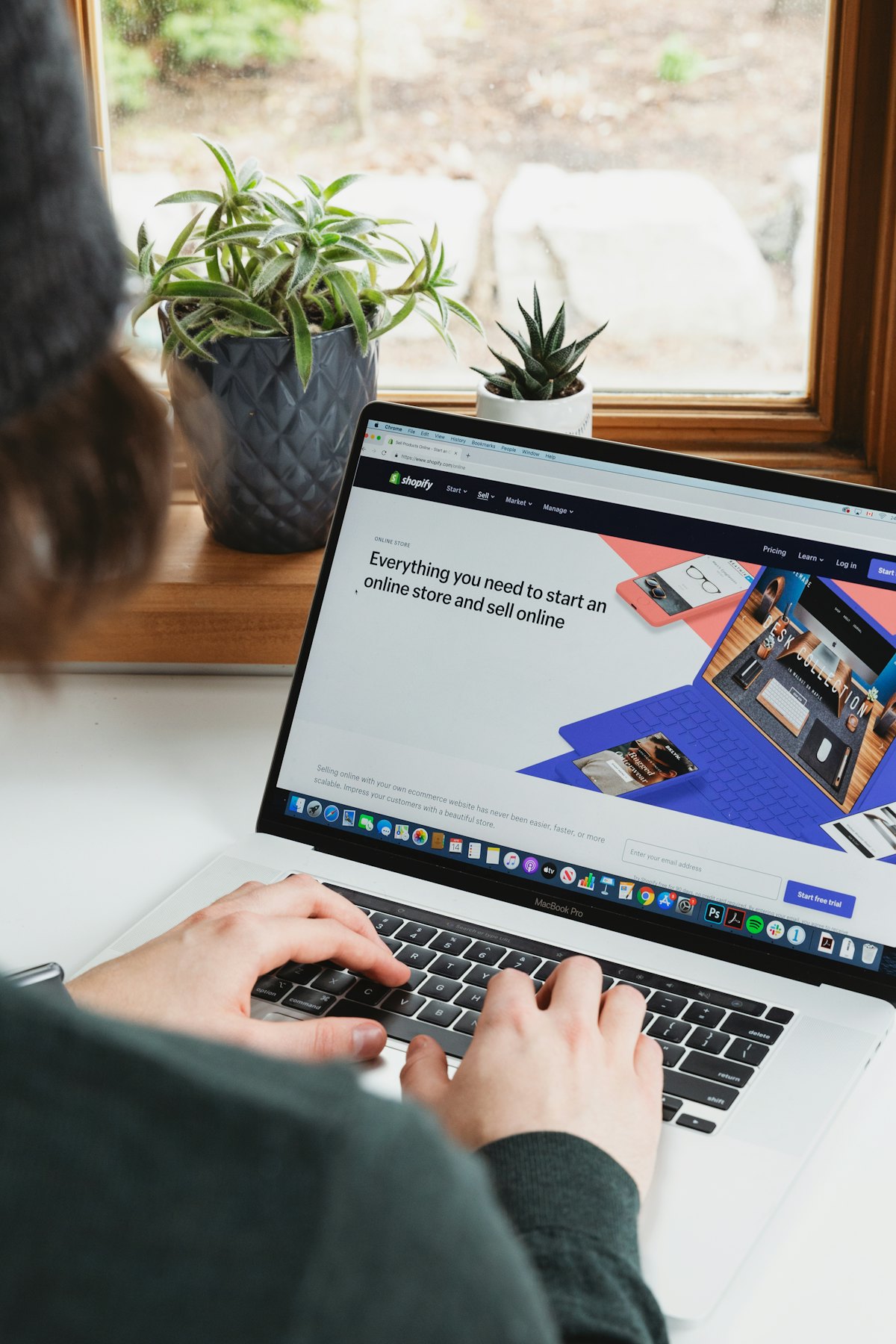Merchant viewing the Shopify online store homepage on a MacBook by a window