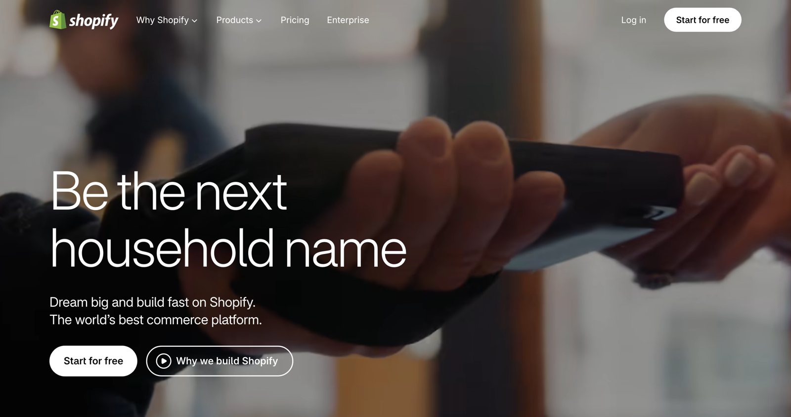 Shopify homepage in 2026 with the headline Be the next household name over a tap-to-pay checkout between two people